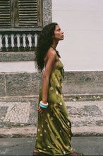 Woman in a green dress with polka dots standing on stone steps.
