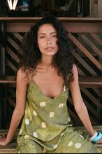 Woman wearing a green polka dot dress sitting on wooden steps.