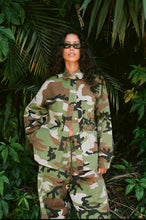 Person wearing a camouflage outfit standing in a jungle setting