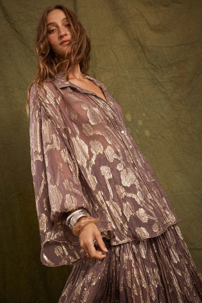 Model wearing the purple Collector Chalm Shirt with a metallic floral pattern and relaxed button-through silhouette against an olive backdrop.