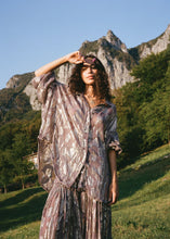 Model wearing the sheer purple floral shirt outdoors, showing the relaxed fit, button front and shimmering metallic finish.