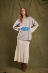Model wearing the oversized grey marl graphic tee with cream lace layers and brown boots, showing the relaxed fit, blue contrast stitching and front artwork.