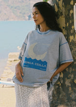 Model wearing the grey marl graphic tee with a cream lace skirt beside a lake, showing the oversized shape, blue stitching and moon-inspired front graphic.