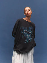 Model wearing a vintage black long-sleeve graphic tee with a light grey maxi skirt, showing the oversized fit, crew neckline and blue dragon graphic across the front