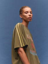 Person wearing a green oversized t-shirt with colorful text on a blue background