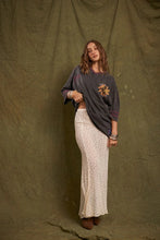 Model wearing the cream lace maxi skirt with an oversized charcoal graphic tee and brown ankle boots, showing the fitted waist, flowing length and softly flared lace silhouette in a full-length front view.