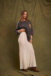 Model wearing the cream lace maxi skirt with an oversized graphic tee and brown ankle boots, showing the long flowing shape, delicate lace texture and gently flared hem in an angled front view.