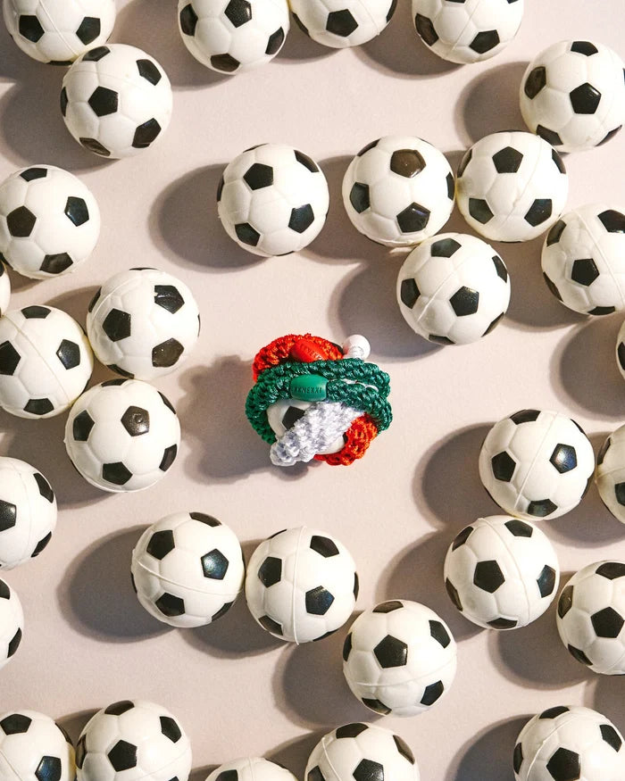 Forrest Green woven hair tie styled with colourful hair ties among miniature black and white soccer balls.