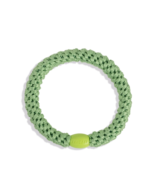 Grass green woven hair tie shown in a circular product view with a contrasting lime green bead on a clean background.
