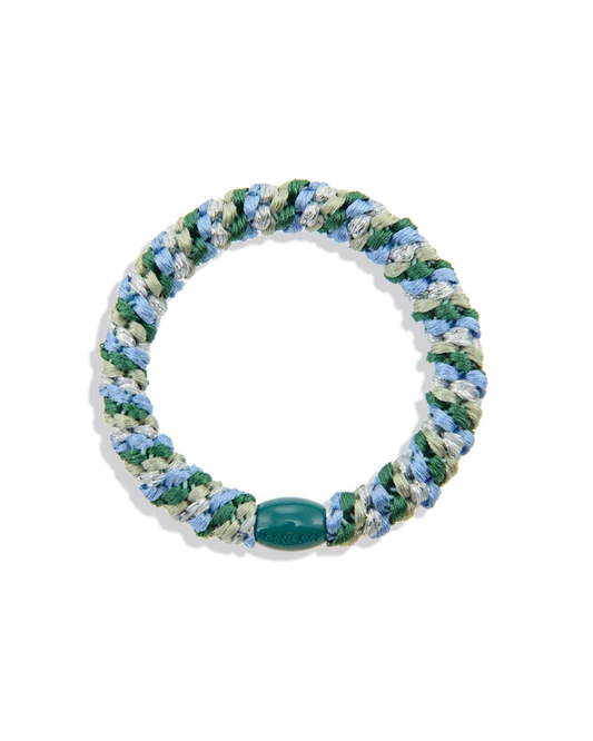 Woven hair tie in mixed green, pale blue, white and silver glitter tones shown in a circular product view with a dark green branded bead.
