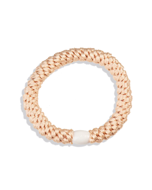 Powder peach woven hair tie shown in a circular product view with a smooth white bead on a clean background.