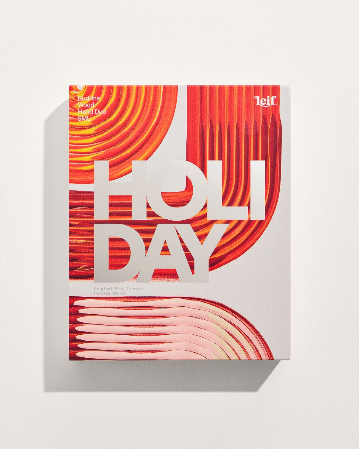 A limited-edition gift box featuring bold red, orange and cream abstract artwork with large white “HOLIDAY” lettering across the front.
