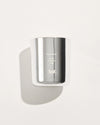 A chrome glass candle vessel with pale wax is shown from the front against a light background, displaying the Flannel Flower label.