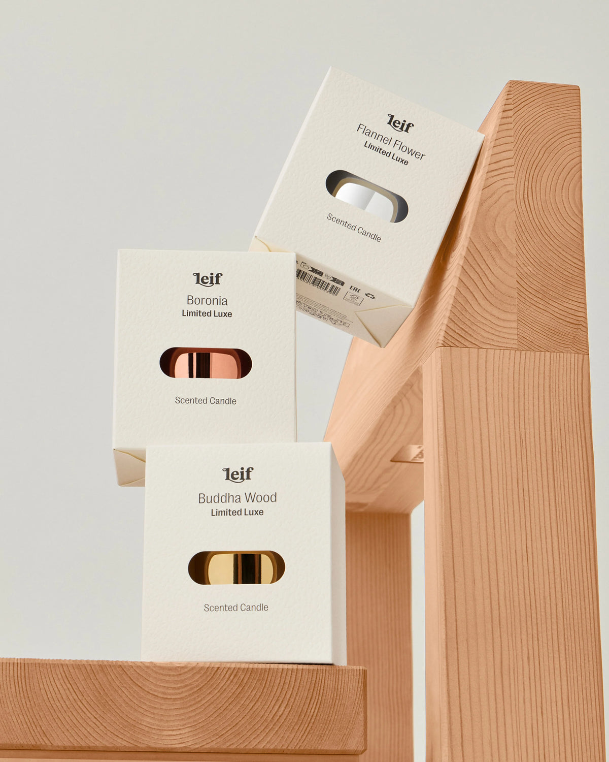 Three cream candle boxes from the Limited Luxe collection are arranged on wooden display blocks, with the Flannel Flower, Boronia and Buddha Wood names visible.
