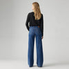 Model wearing the Levi's 318 Shaping Wide Leg Jeans in the Clever Girl wash, showing the back pockets, Levi's tab and wide-leg silhouette in a back view.