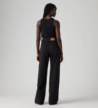 Model wearing Levi’s black high-rise wide-leg jeans with a black sleeveless top, showing the two back pockets, waistband patch and relaxed full-length fit, back view