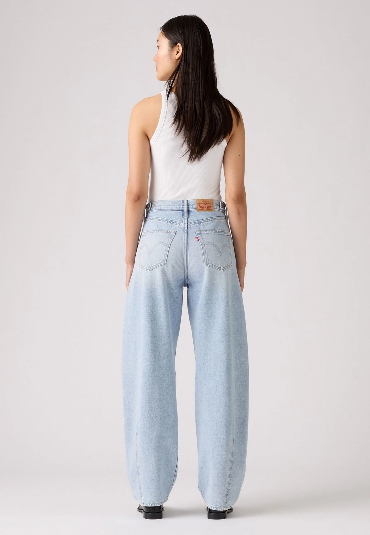 Back view of the light-wash jeans showing the back pockets, waistband patch and relaxed leg shape.