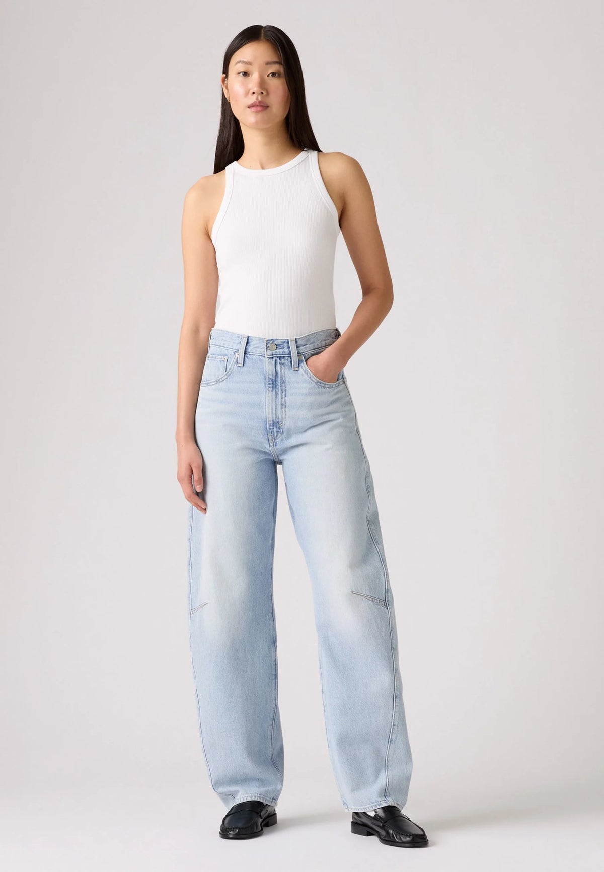 Front view of the light-wash barrel jeans styled with a white tank top and black loafers, highlighting the high waist and loose legs.
