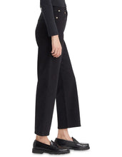 A model wears the black straight-leg ankle jeans in a side studio view showing the high-rise waist and cropped length.
