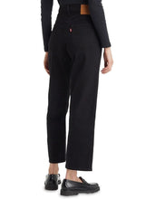 A model wears the black ankle-length jeans in a rear studio view showing the back patch pockets and straight-leg fit.
