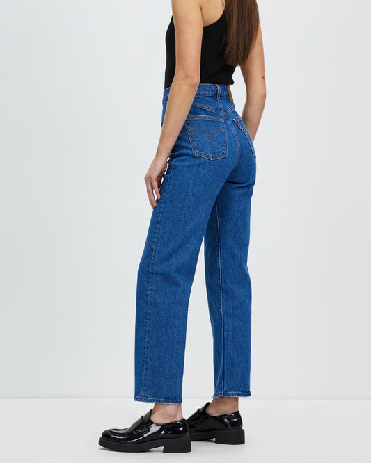 Person wearing blue jeans and black shoes on a white background