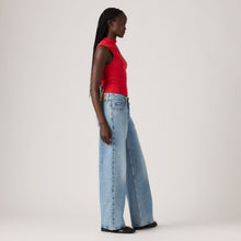 Woman wearing a red top and blue jeans on a white background
