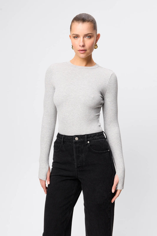 Woman wearing a gray long-sleeve top and black pants on a white background
