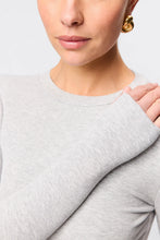 Close-up of a person wearing a light gray sweater with a neutral background