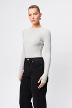 Woman wearing a gray long-sleeve top and black pants on a white background
