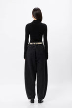 Person wearing a black turtleneck and dark jeans on a white background