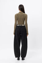 Person wearing a green corduroy shirt and black pants on a white background
