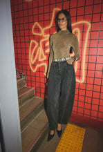 Person standing in front of a red grid-patterned wall with graffiti.