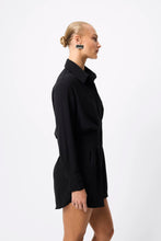 A model wears the black collared mini dress in a side studio view showing its curved hem and fitted waist.