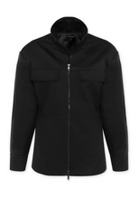 The black anorak is displayed from the front, showing its long sleeves, two-way zip and flap chest pockets.