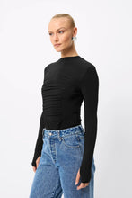 A model wears the Mossman Iris Top in black with blue jeans in an angled front studio view.
