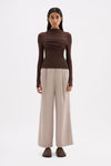 Chocolate long sleeve top styled with neutral wide-leg trousers in a full-length front view.