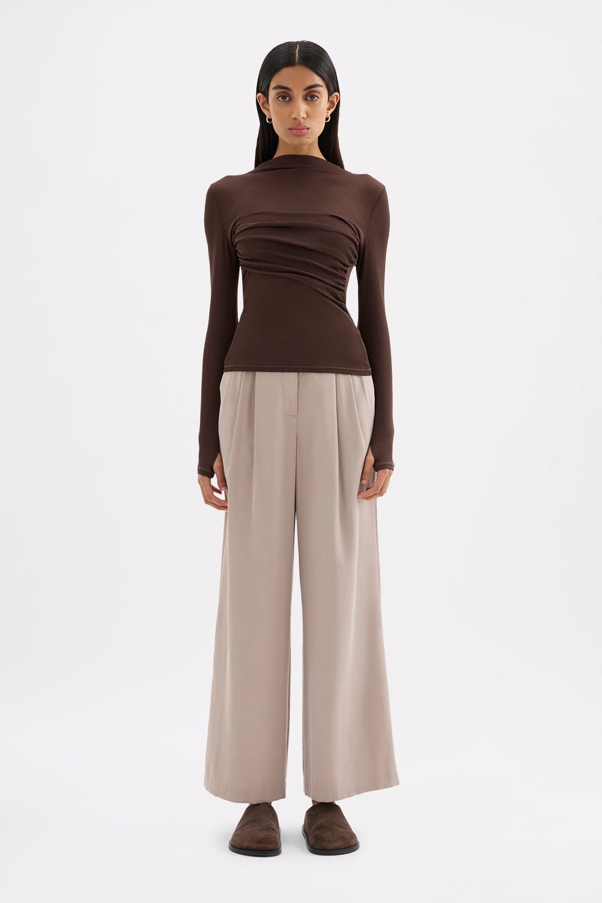 Chocolate long sleeve top styled with neutral wide-leg trousers in a full-length front view.