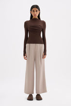 Chocolate long sleeve top styled with neutral wide-leg trousers in a full-length front view.