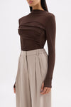 Three-quarter view highlighting the draped front detail, long sleeves and slim fit.