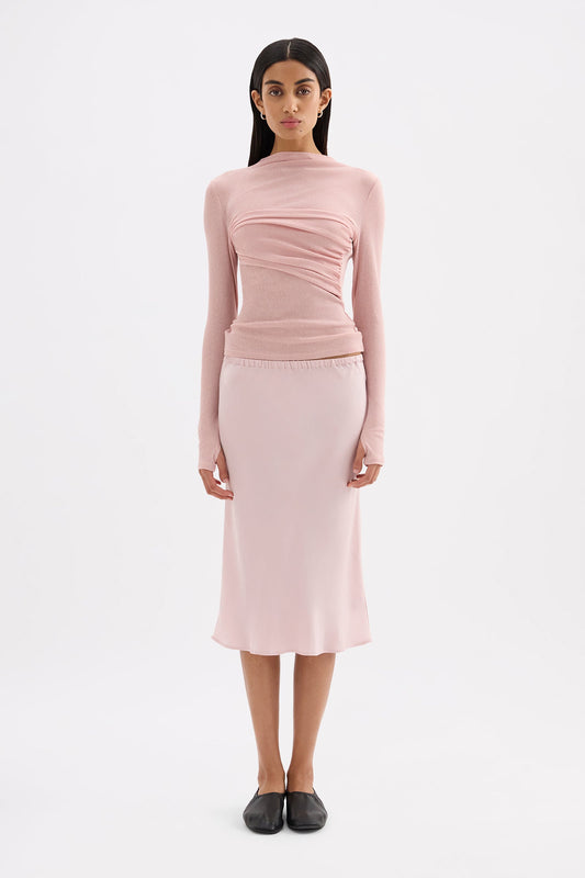 Pink fitted long sleeve top styled with a matching midi skirt in a full-length front view.