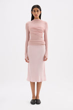 Pink fitted long sleeve top styled with a matching midi skirt in a full-length front view.