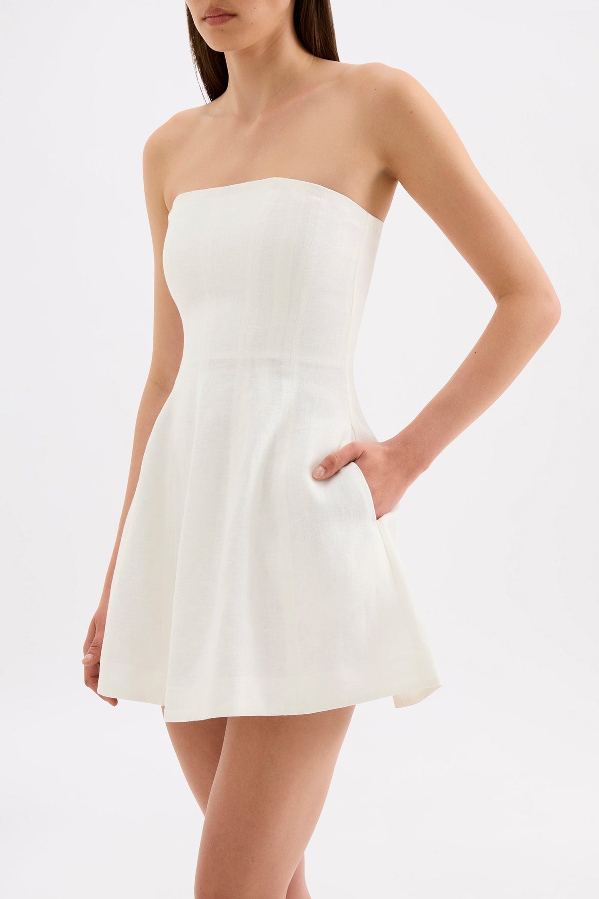 Close-up view of the white mini dress showing the strapless neckline, fitted bodice, full skirt and side pocket.