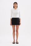 A model wears a black skort with a mid-rise waist and slight A-line shape in a full front studio view.