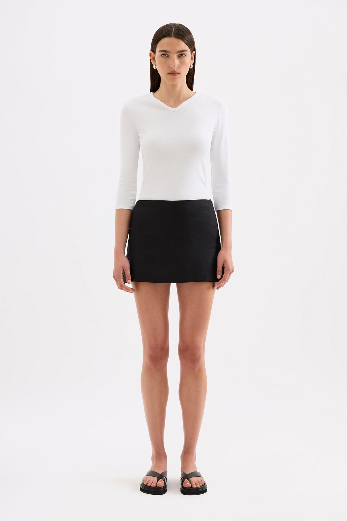 A model wears a black skort with a mid-rise waist and slight A-line shape in a full front studio view.