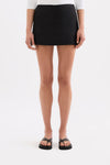 Close-up front view of the black skort showing the smooth waistband, short length and straight hem.