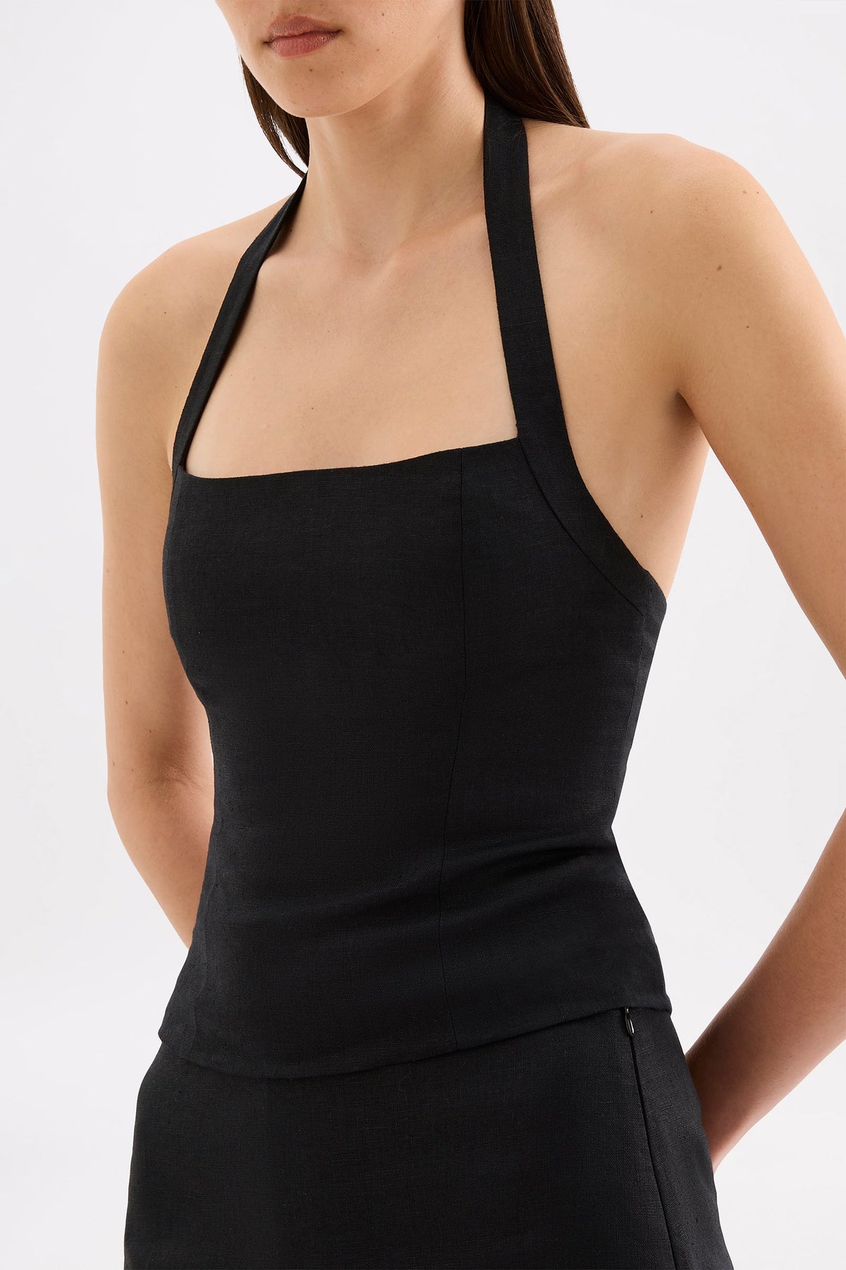 Close-up view of the black top showing the straight neckline, halter straps and fitted bodice.