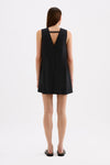 Back view of the black mini dress showing the wide shoulder straps, triangular back cut-out and loose full skirt.