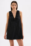 Close-up front view of the black mini dress showing the deep V neckline, gathered shoulder detailing and tied keyhole opening.
