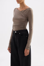 Three-quarter side view showing the fitted silhouette, long sleeves and asymmetric draping.
