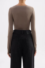 Back view of the truffle long sleeve top styled with black jeans against a white studio background.